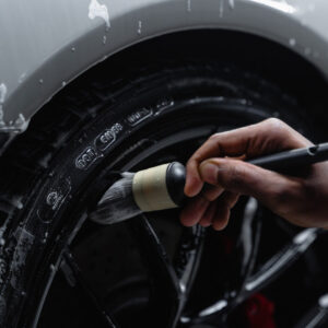 Man using small brush to detail car tires