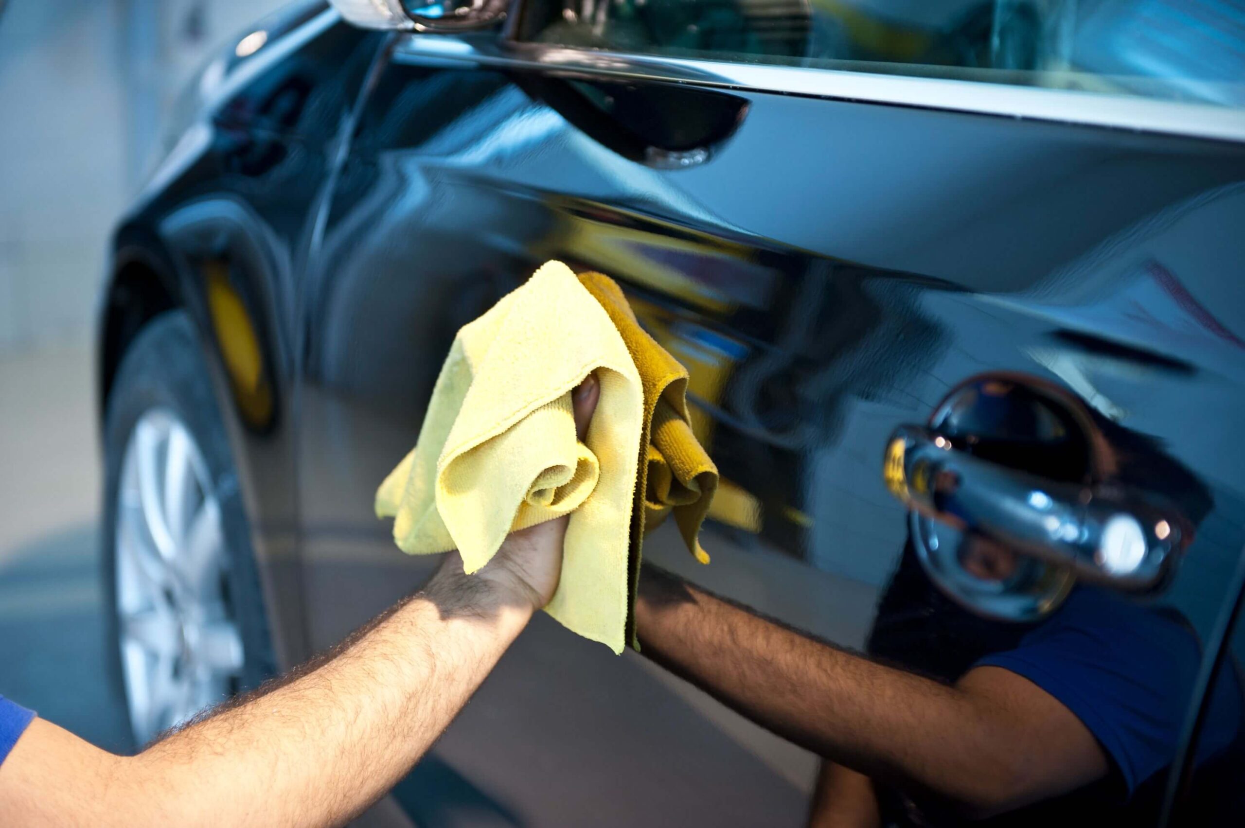 detailer using waterless car wash method to clean the exterior of a vehicle