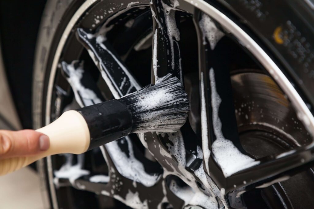 Man cleaning car rims with small detail brush