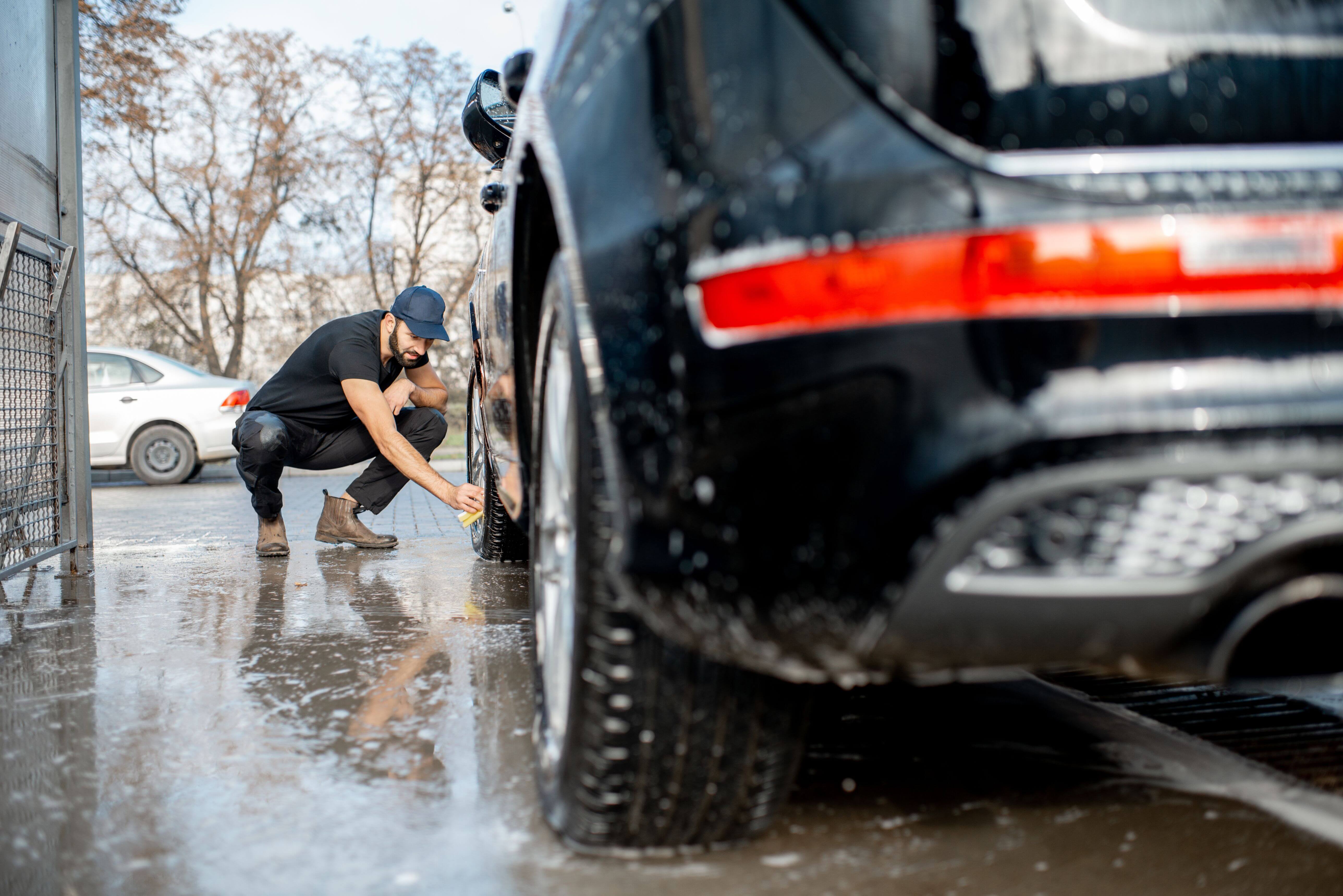 Car detailer washing black car with soft cloth