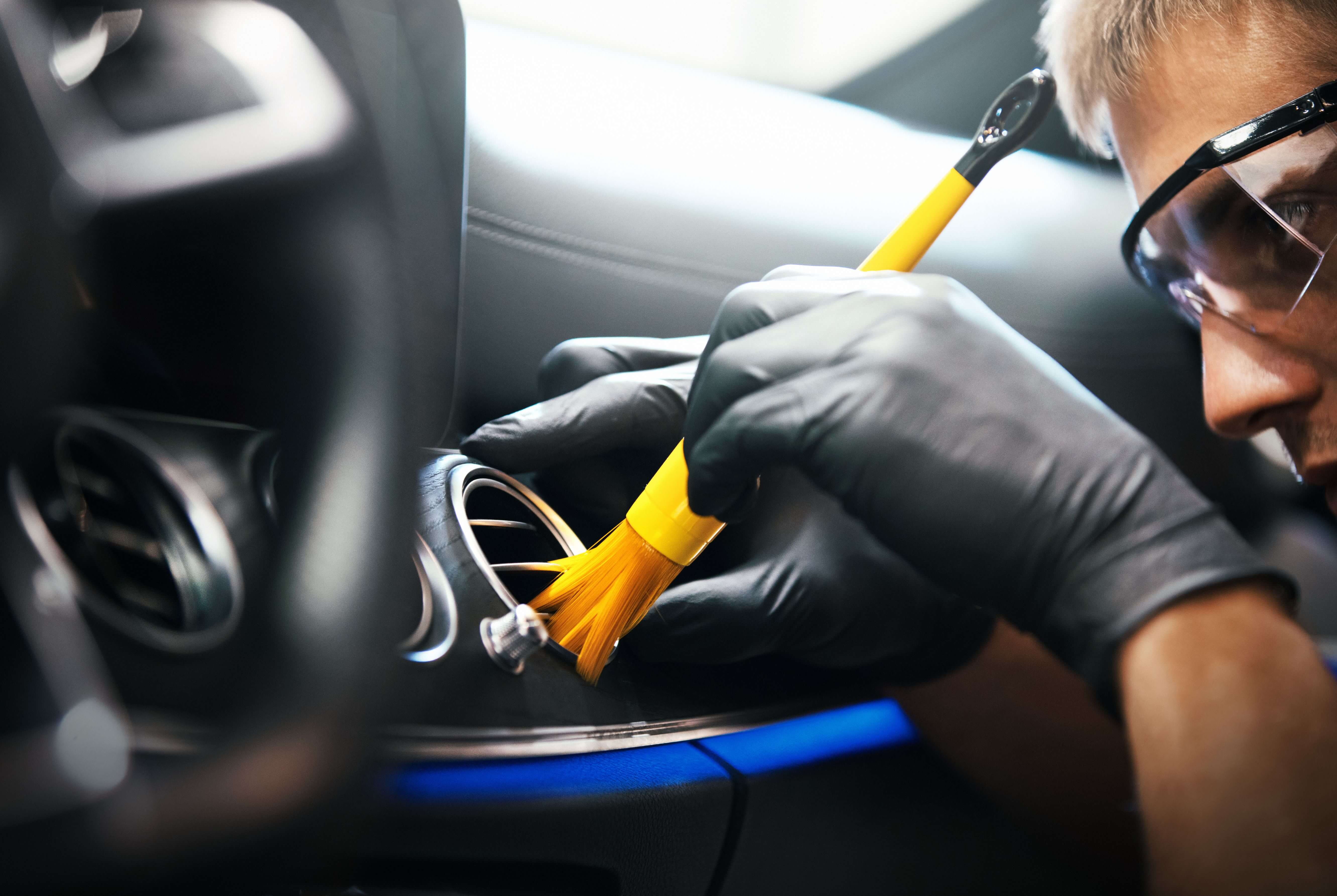 Man cleaning car dashboard with a detailing brush