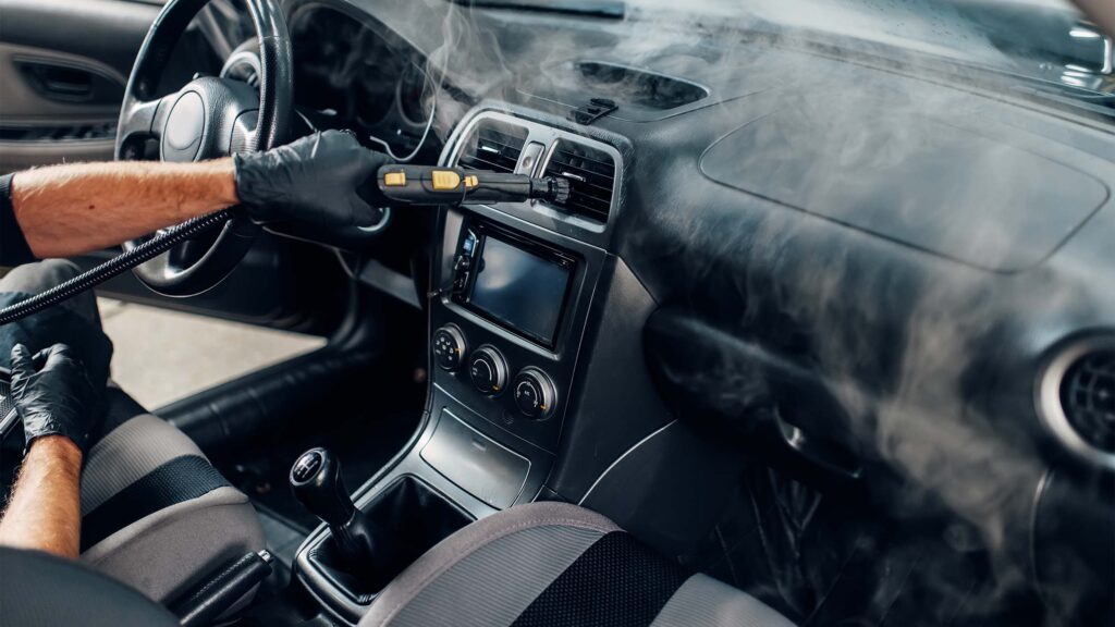 car detailer sanitizes car ventilation system with steam cleaner