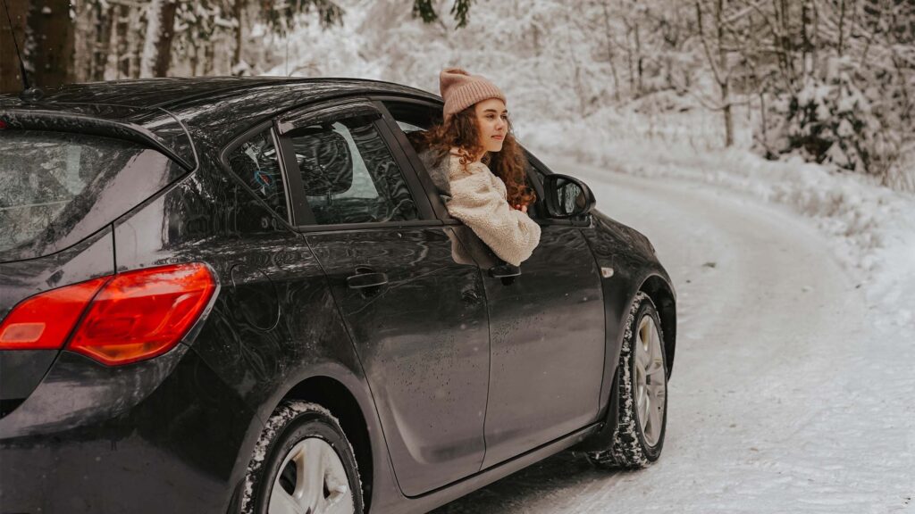 woman leaning out of black vehicle on snowy day