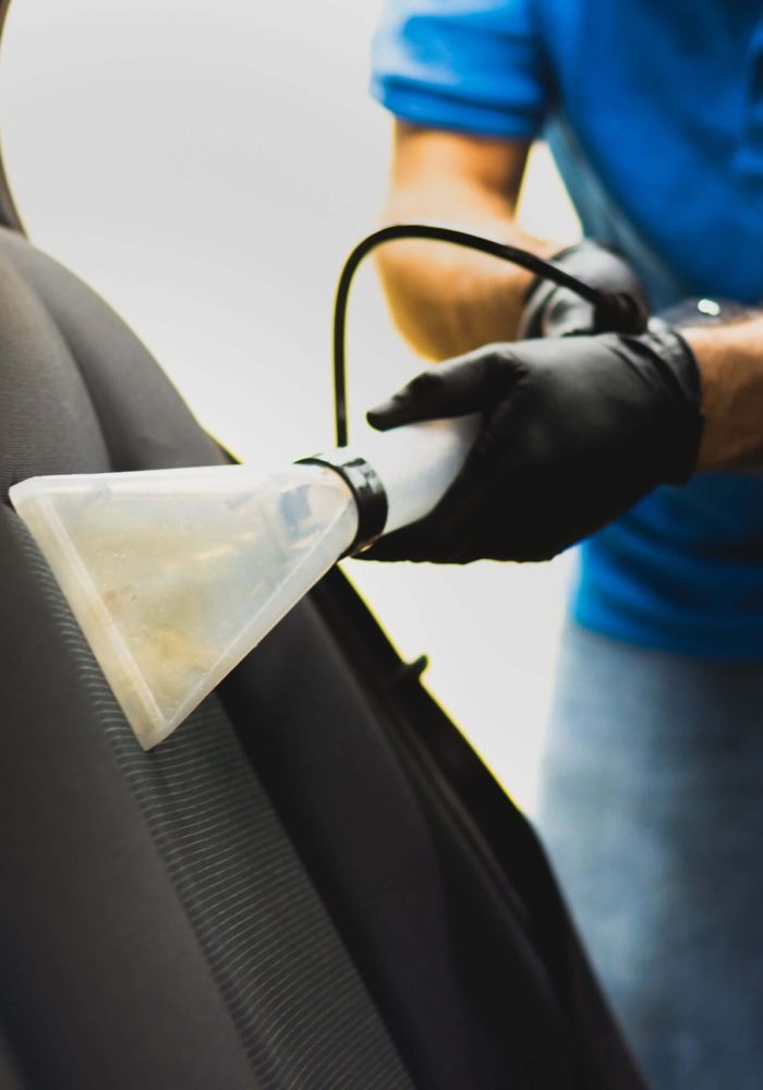Detailer vacuuming grey car seats