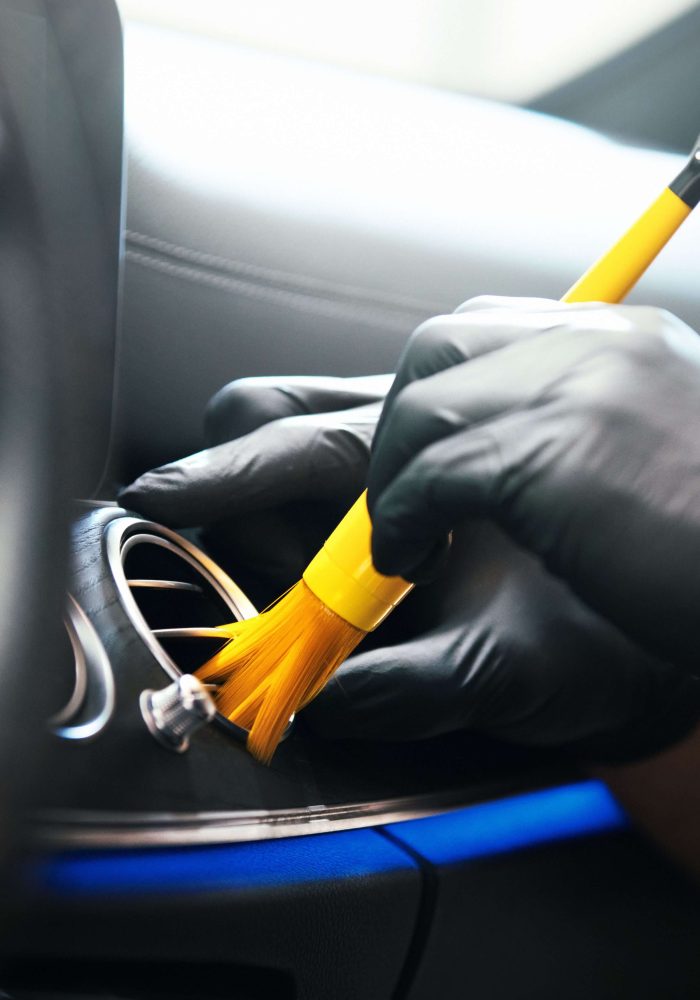 Man cleaning car dashboard with a detailing brush